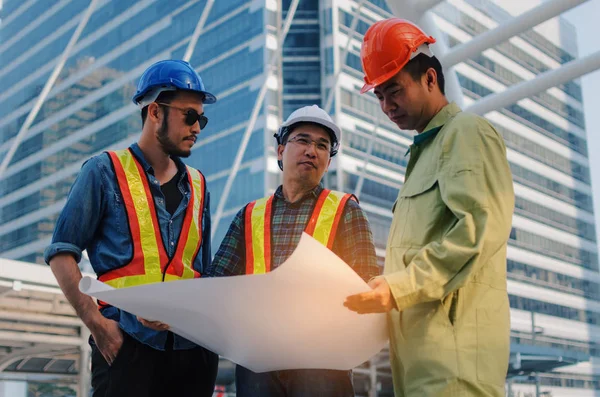 エンジニア 技術者や建築の近代的な都市の建物の背景 建設現場 ビジネス および労働者の概念設計と計画に関する計画安全ヘルメットと建築家のグループ — ストック写真