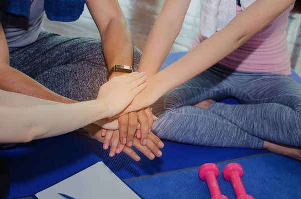 close up of sport people team planning to reach their goal and doing high five together sitting on yoga mat in fitness gym, exercise, training, workout, partnership, success and teamwork concept