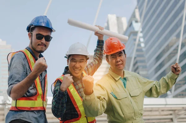 最后我们做到了 工程师 技术员和建筑师的团队在现代城市建筑背景 施工现场和行业理念的共同努力下 尖叫着展示他们的双手 — 图库照片