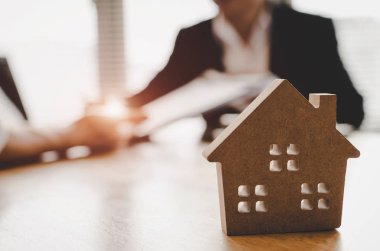 ahşap ev modeli, yatırım, ev kredisi sözleşmesi, gayrimenkul, sigorta, arkasında emlakçı ofisinde Emlak komisyoncusu ile ev satın almak için imza sözleşme müşteri satın almak ve satmak ev kavramı