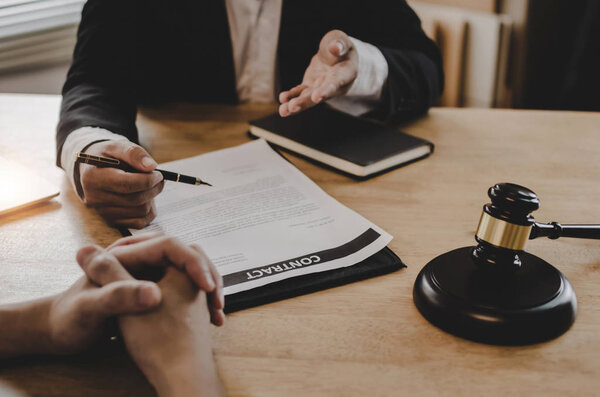 юридические консультанты, нотариус или юрист, обсуждающие договорные документы с клиентом и деревянным судьей молотком на столе в офисе суда, бизнесе, праве правосудия, страховании и концепции юридического обслуживания
