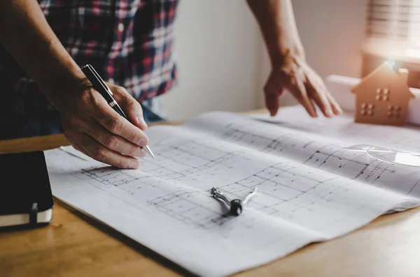 hand professional architect, engineer or interior hands drawing with blueprint on workplace desk in office center at construction site, contractor, construction, engineering and business concept