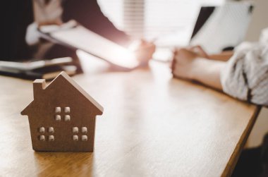 ahşap ev modeli, yatırım, ev kredisi sözleşmesi, gayrimenkul, sigorta, arkasında emlakçı ofisinde Emlak komisyoncusu ile ev satın almak için imza sözleşme müşteri satın almak ve satmak ev kavramı