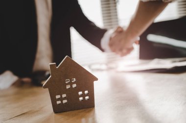 Ev modeli, yatırım, ev kredisi sözleşmesi, arkasında emlakçı ofisinde ev satın almak için sözleşme imzalama sonra Emlak broker Yöneticisi el sallamak için müşteri satın almak ve satmak ev kavramı