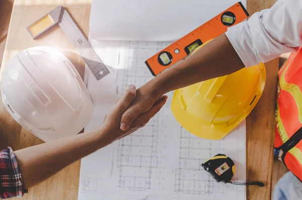 top view construction worker team contractor hand shake after finishing up business meeting to greeting start up project contract in construction site building, teamwork, partnership, industry concept