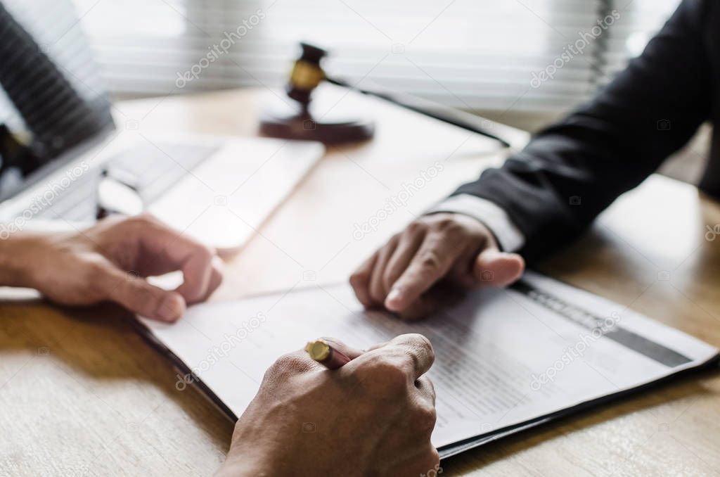 client customer signing contract and discussing business with legal consultants, notary or justice lawyer with laptop computer and wooden judge gavel on desk in courtroom office, legal service concept