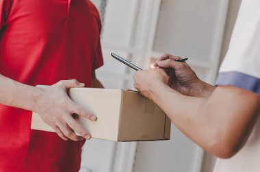 Eve teslim hizmet adam kırmızı üniforma ve genç adam müşteri dijital cep telefonu evde kurye, ekspres teslimat ve online alışveriş kavramı parsel posta kutusu alma imza ekleme