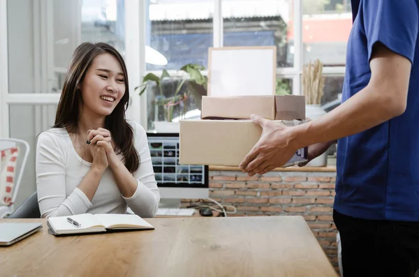 home delivery service man in blue uniform and young woman customer appending signature in digital mobile phone receiving parcel post box from courier at home, express delivery, online shopping concept