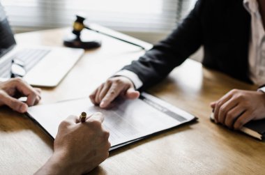 sözleşme imzalama ve mahkeme ofis, yasal hizmet kavramı masa üzerinde yasal danışmanlar, dizüstü bilgisayar ve ahşap Yargıç tokmak ile noter veya adalet avukat ile iş tartışırken istemci müşteri