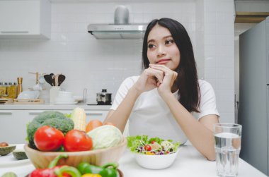 güzel genç Asyalı kadın ince vücut diyet ve beslenme beyaz gömlekli sağlıklı gıda, oturma mutfak iç içinde ev, yaşam tarzı, sağlıklı, iyi taze sebze salatası diyet yiyecek ve içecek konsepti