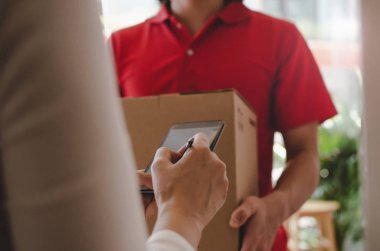 eve teslim hizmet adam kırmızı üniforma ve genç kadın müşteri dijital cep telefonu parsel posta kutusu alma evde kurye, ekspres teslimat, online alışveriş kavramı imza ekleme