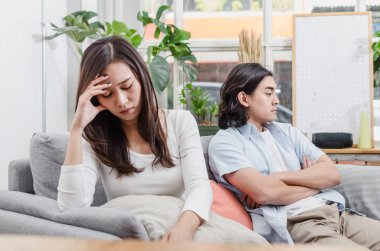 kavga sahip ve oturan kanepede birlikte, dövüşten sonra onun içinde ev iç arkasında kocası ile üzüntü genç Asya karısı üzgün çift, aşk, boşanma çift, Aile sorunları ve ilişki kavramı