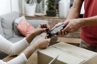 eve teslim hizmet adam kırmızı üniforma ve genç kadın müşteri dijital cep telefonu parsel posta kutusu alma evde kurye, ekspres teslimat, online alışveriş kavramı imza ekleme