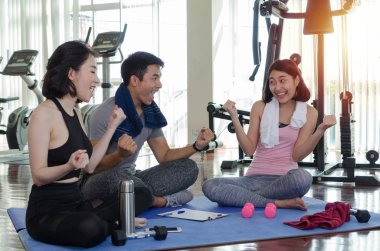 Sportif gençlerin grup neşelendirmek ve birlikte yoga mat fitness salonunda egzersiz yaptıktan sonra oturup gülüyor egzersiz sabah, cesaret, eğitim, ortaklık, başarı ve ekip çalışması kavramı