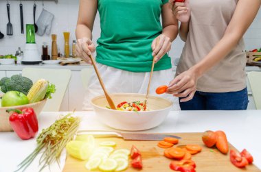 Diyet. Yeşil gömlek ayakta iki genç güzel kadın ve ev, sağlıklı yaşam, yemek, sağlıklı gıda ve diyet konsepti modern mutfakta iyi sağlıklı için kase sebze salatası hazırlanıyor