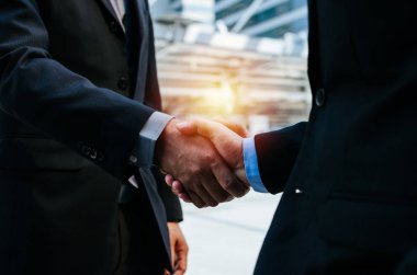 Anlaşma. modern şehirde yeni proje sözleşme toplantısı sırasında ortağı ile el sıkışma takım elbise iki genç işadamı yatırımcı yakın, yatırım, iş toplantısı, el sıkışma ve ortaklık kavramı