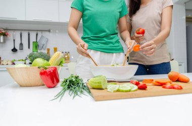Diyet. Yeşil gömlek ayakta iki genç güzel kadın ve ev, sağlıklı yaşam, yemek, sağlıklı gıda ve diyet konsepti modern mutfakta iyi sağlıklı için kase sebze salatası hazırlanıyor