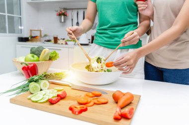 Diyet. Yeşil gömlek ayakta iki genç güzel kadın ve ev, sağlıklı yaşam, yemek, sağlıklı gıda ve diyet konsepti modern mutfakta iyi sağlıklı için kase sebze salatası hazırlanıyor