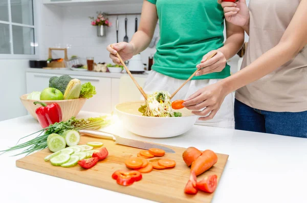 Diyet. Yeşil gömlek ayakta iki genç güzel kadın ve ev, sağlıklı yaşam, yemek, sağlıklı gıda ve diyet konsepti modern mutfakta iyi sağlıklı için kase sebze salatası hazırlanıyor