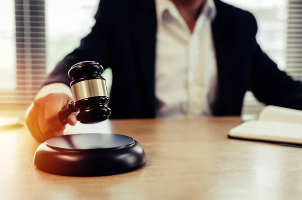 justice lawyer in black suit knocking wooden judge gavel with documents on workplace desk in courtroom office, consultant lawyer, occupation, business adviser, justice law and legal service concept