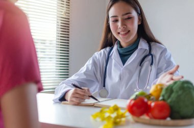 Sağlıklı. dostane beslenme uzmanı kadın doktor ya da ofis hastanesinde masada asya genç hasta ile diyet planı hakkında konuşurken oldukça tıbbi, beslenme, gıda bilimi, sağlıklı gıda ve diyet kavramı