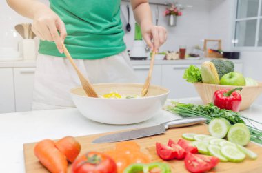 Diyet. Yeşil gömlek ayakta genç güzel kadın ve ev, sağlıklı yaşam, yemek, sağlıklı gıda ve diyet konsepti modern mutfakta iyi sağlıklı için kase sebze salatası hazırlanıyor