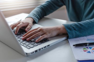 çalışma ve evde ofiste masada dizüstü bilgisayar ve belge kullanarak, web, sosyal ağ, online, finans, yatırım ve dijital teknoloji kavramı arama genç kadın klavye üzerinde el