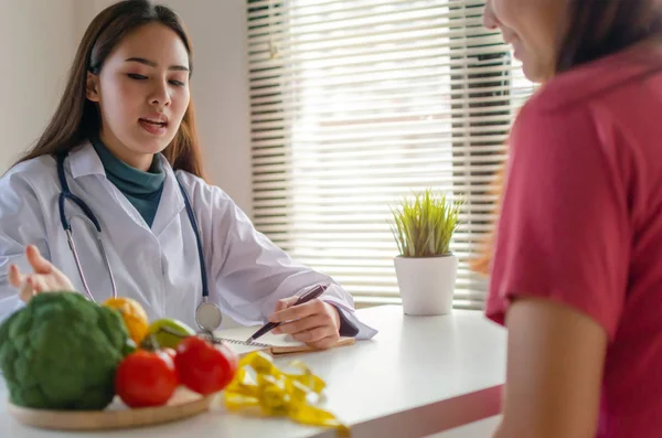 Beslenme. dost beslenme kadın doktor ya da ofis hastanesinde masada asya genç hasta ile diyet planı hakkında konuşurken oldukça tıbbi, beslenme, gıda bilimi, sağlıklı gıda, diyet kavramı