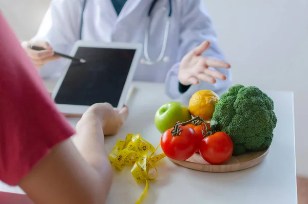 tablet kullanarak ve ofis hastanesinde laboratuvar odasında masada hasta ve sebze ile diyet planı hakkında konuşmak dostu beslenme kadın doktor, gıda bilimi, sağlıklı gıda ve diyet kavramı