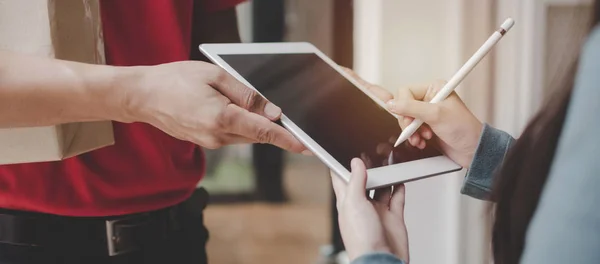 web afiş. evde kuryeden parsel posta kutusu almak için kırmızı üniformalı teslimat servisi adam ile dijital mobil tablet kalem imza kullanarak kadın, ekspres teslimat ve alışveriş online kavram