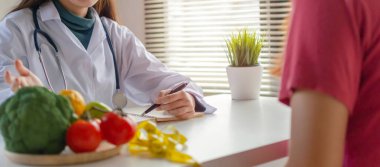 Panoramik afiş. Beslenme. ofis hastanesinde genç hastaya sebze ile diyet planı hakkında konuşan dost beslenme uzmanı kadın doktor doktor, beslenme, gıda bilimi, sağlıklı gıda kavramı