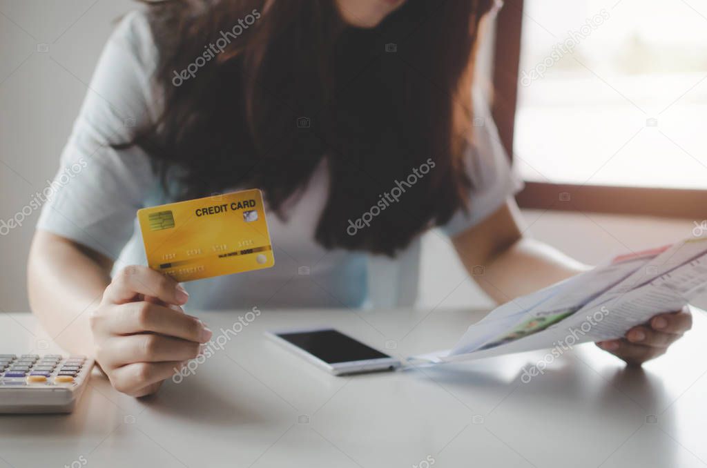 asian young woman holding credit card and analysis with family budget cost bills and mobile phone on desk in home office, plan money cost saving, investment, business finance and expenses concept
