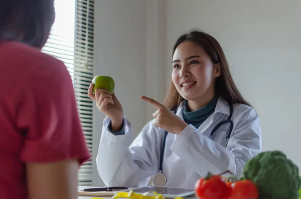 Nutritional. friendly nutritionist female doctor medical talking about diet plan with green apple and vegetable to young patient woman in office hospital, nutrition, food science, healthy food concept