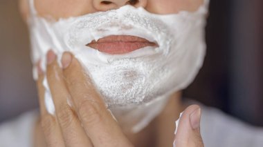 Genç adam traş olur, yüzünde köpükle jilet izi olur.