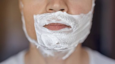 Genç adam traş olur, yüzünde köpükle jilet izi olur.