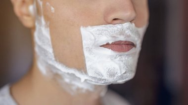 Genç adam traş olur, yüzünde köpükle jilet izi olur.