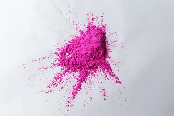 Holi festivali için boyalar, pembe pigmentli kırılgan boyalar beyaz bir yüzeyde yatıyor.