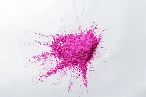Holi festivali için boyalar, pembe pigmentli kırılgan boyalar beyaz bir yüzeyde yatıyor.
