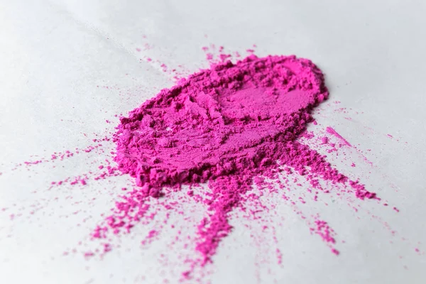 Holi festivali için boyalar, pembe pigmentli kırılgan boyalar beyaz bir yüzeyde yatıyor.