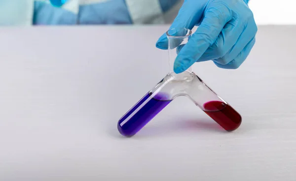 Kimyager iki sıvıyı karıştırıyor, arka planda fotoğraf var.