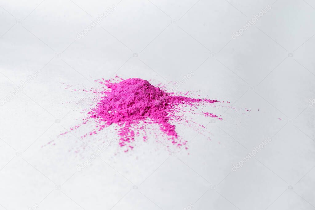 paints for the Holi festival, pink pigmented friable paints lie on a white surface