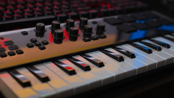 Клавіатура музичного синтезатора або мідіклавія в аматорській студії звукозапису, клавіатура відображає монітор та інше освітлення студії — стокове фото