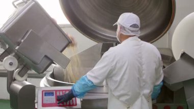 Bir et işleme tesisinde sosis üretimi için büyük bir çelik öğütücü işleten işçi