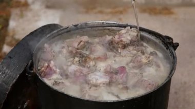 Çiftçi Pastirma ya da kuzu eti pişiriyor, dışarıda bir kazanda.