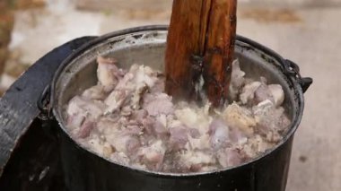 Çiftçi Pastirma ya da kuzu eti pişiriyor, dışarıda bir kazanda.