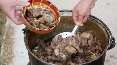 Çiftçi Pastirma ya da kuzu eti pişiriyor, dışarıda bir kazanda.