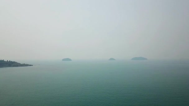 Fumaça sobre o mar da Tailândia. Pequenas ilhas são visíveis à distância, e o céu é coberto com uma gota branca de fumaça. Água verde com ondas pequenas. O fumo vem do Camboja. Drone de tiro — Vídeo de Stock