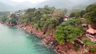 Yeşil Chang adası Kamboçya 'daki bir yangından dolayı dumanla kaplandı. Yeşil ağaçlar, palmiye ağaçları ve tepeler sis bulutlarıyla kaplıdır. Oteller denizin önündeki bir uçurumun üzerinde duruyor. Turkuaz su.