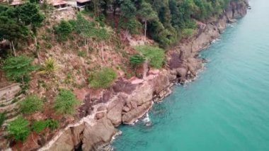 Yeşil Chang adası Kamboçya 'daki bir yangından dolayı dumanla kaplandı. Yeşil ağaçlar, palmiye ağaçları ve tepeler sis bulutlarıyla kaplıdır. Oteller denizin önündeki bir uçurumun üzerinde duruyor. Turkuaz su.