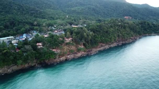 Dawn op Chang eiland. Turkoois helder water met golven reflecteert het milieu. Lichte wolken met roze kleur, groene heuvels, palmbomen. Een scherpe druppel in het water. Schieten van een drone. Thailand. — Stockvideo